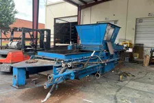 Thumbnail for Industrial blue metal equipment with hoses and pipes inside warehouse near forklift and loading docks.