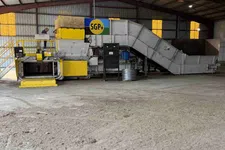 Thumbnail for Industrial processing machine with yellow and grey parts inside a large warehouse with metal roof beams.