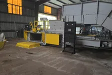 Thumbnail for Industrial machinery with yellow panels inside a large factory with high ceilings and orange windows.