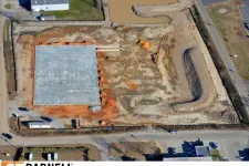 Thumbnail for Aerial view of a construction site with concrete foundation and earthmoving activities in progress.