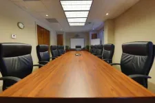 Thumbnail for Spacious modern conference room with long wooden table, black leather chairs, projector, and neutral walls.