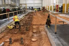 Thumbnail for Construction workers preparing a large industrial site foundation with soil excavation and concrete flooring inside a warehouse.