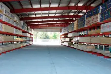 Thumbnail for Warehouse with organized shelves storing lumber and building materials under a red steel roof structure.