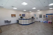 Thumbnail for Clean postal service counter area with tiled floor, information display, and water fountains in a bright room.