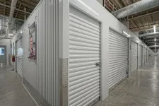 Thumbnail for Interior view of a self storage facility with rows of closed metal roll-up doors and a concrete floor.