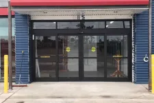 Thumbnail for Glass automatic sliding doors with yellow safety stickers at the entrance of a commercial building under construction.