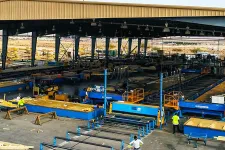 Thumbnail for Wide view of an industrial metal fabrication workshop with workers and machinery under a large steel shed.