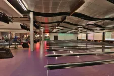 Thumbnail for Interior view of a spacious bowling alley with multiple lanes, seating areas, and a pizza counter in the back.