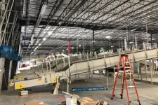 Thumbnail for Industrial conveyor belts and equipment under construction inside a large warehouse with high ceilings and exposed beams