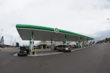 Thumbnail for Wide view of a BP gas station with cars refueling under a large green and white canopy on a cloudy day.