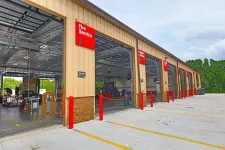 Thumbnail for Exterior shot of a multi-bay auto service center with Tire Service and Wheel Service bays open under a clear sky.