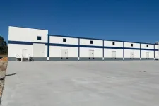 Thumbnail for White and blue industrial warehouse with multiple loading dock doors under a clear blue sky