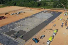 Thumbnail for Aerial view of concrete foundation being poured at a large construction site with trucks and workers.