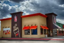 Thumbnail for Dunkin' Donuts storefront with bold orange awnings and signage under a dramatic cloudy sky.
