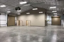 Thumbnail for Spacious empty warehouse interior with polished concrete floor, high ceiling, and large roll-up doors.