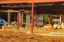 Thumbnail for Steel framework and concrete foundation of a building under construction with workers and equipment visible