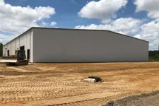 Thumbnail for New large metal warehouse on construction site with bulldozer and clear blue sky with clouds