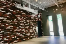 Thumbnail for Industrial-style room with exposed brick wall, high ceiling, large windows, and concrete floor.