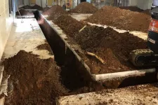 Thumbnail for Indoor construction site with deep trenches dug in concrete floor and piles of soil around machinery.