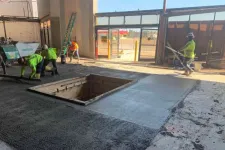 Thumbnail for Construction workers smoothing fresh concrete around a large rectangular pit inside a building.