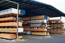 Thumbnail for Covered outdoor lumber storage with multiple stacks of wooden planks organized on metal racks.