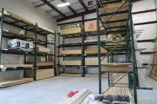 Thumbnail for Wood sheets and building materials organized on green metal shelves in a spacious warehouse with concrete floor.