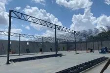 Thumbnail for Steel framework construction in progress inside a large building under a cloudy blue sky.