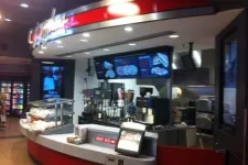 Thumbnail for Modern fast food counter with digital menu screens and beverage machines inside a convenience store