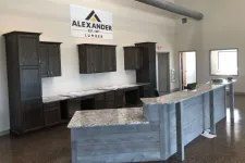Thumbnail for Modern office interior with granite countertop reception desk and dark wood cabinets under an Alexander Lumber sign.