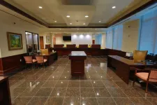 Thumbnail for Spacious bank lobby with polished tiled floors, wooden desks, chairs, and large windows with blinds.