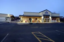 Thumbnail for Exterior view of a well-lit commercial building with parking lot and signage at dusk.