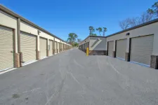 Thumbnail for Outdoor self-storage facility with multiple beige roll-up garage doors under a clear sky