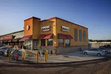 Thumbnail for Popeyes Louisiana Kitchen restaurant building with cars parked outside on a clear day.