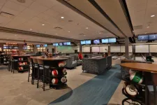 Thumbnail for Modern bowling alley interior with seating, tables, bowling balls, and multiple lanes with screens.