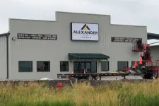 Thumbnail for Alexander Lumber building with signage displaying services like decks, rails, kitchen design, and exterior siding