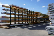 Thumbnail for Outdoor lumber storage rack with long wooden beams and stacked West Fraser LVL packages on a sunny day.
