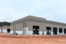 Thumbnail for Large industrial warehouse building under construction with multiple loading dock doors and red soil ground.