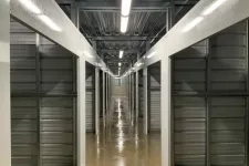 Thumbnail for Long interior hallway with rows of closed metal storage unit doors and polished concrete floor under fluorescent lights