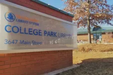 Thumbnail for Exterior view of College Park Library sign on brick wall with autumn tree and building in background