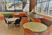 Thumbnail for Bright modern room with round tables featuring leaf designs and colorful chairs under large windows with natural light.