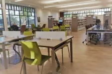 Thumbnail for Modern library interior with green chairs, study tables, computer stations, and large windows letting in natural light.