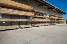 Thumbnail for Outdoor lumber storage racks holding various types of wood planks under clear blue sky at a hardware store.