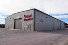 Thumbnail for Large gray metal industrial building with Mead Lumber signage and drive-thru entrance under a cloudy sky