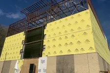 Thumbnail for Construction site with steel framework and yellow exterior sheathing panels under a clear blue sky
