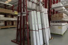 Thumbnail for Warehouse racks storing boxed pocket door frames and lumber in an organized industrial setting.