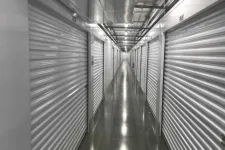Thumbnail for Long indoor hallway with metal roll-up doors on both sides and polished concrete floor in a storage facility