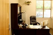 Thumbnail for Cozy office setup with dark wood desk, leather chair, paperwork, filing system, and a fish mounted on the wall.