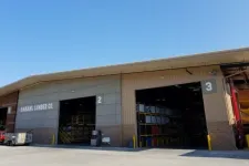 Thumbnail for Exterior view of Ganahl Lumber Co. warehouse with open bays numbered 2 and 3 under clear blue sky.
