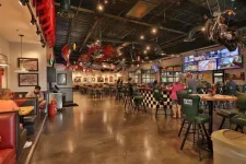 Thumbnail for Spacious motorcycle-themed bar and restaurant with patrons, multiple TVs, and unique decor including hanging motorcycles.