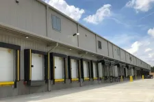 Thumbnail for Row of industrial warehouse loading docks with closed dock doors and clear blue sky above.
